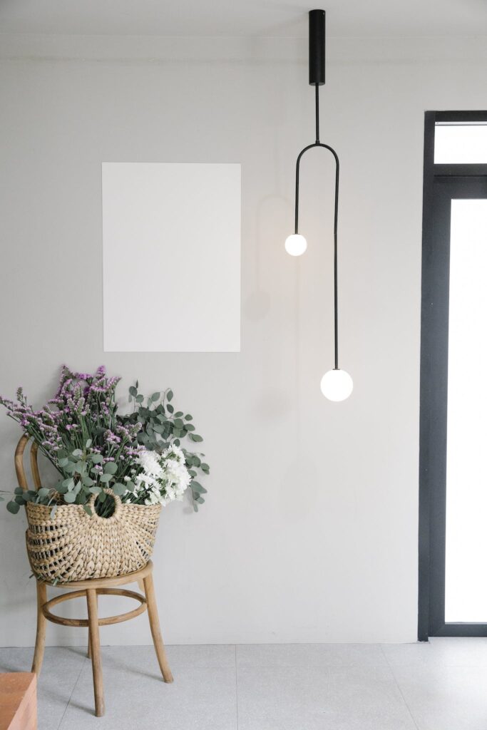 Bouquet of fresh wildflowers in wicker basket placed near wall with white mockup